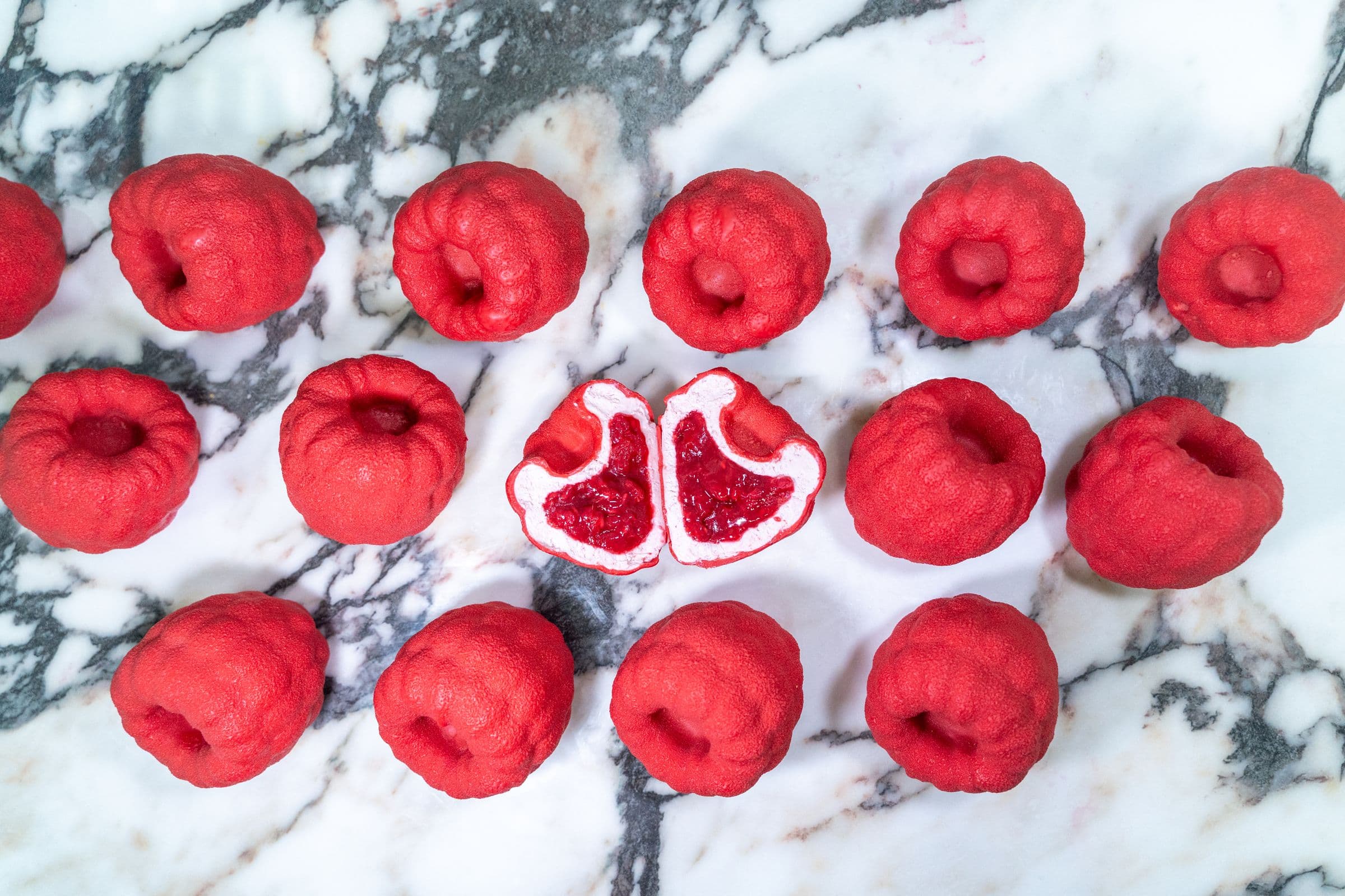 Raspberry pastries, whole, on white marble